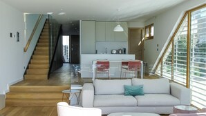 A modern interior with a staircase, a living area with a sofa and coffee table, and a kitchen area with a dining set. - Beach front home in Petrcane (Petrcane)