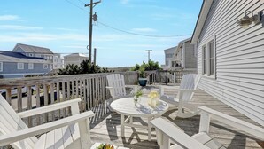 A deck with outdoor furniture, a table, and a potted plant. - Steps to the beach. Canal front with new dock. Clean, Cozy Getaway.   (Surf City)