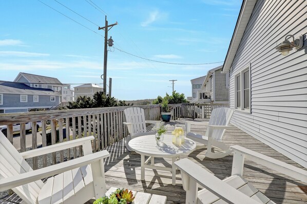 A deck with outdoor furniture, a table, and a potted plant. - Steps to the beach. Canal front with new dock. Clean, Cozy Getaway. (Surf City)
