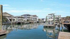 A marina with docked boats, wooden walkways, and waterfront buildings. - Steps to the beach. Canal front with new dock. Clean, Cozy Getaway.   (Surf City)