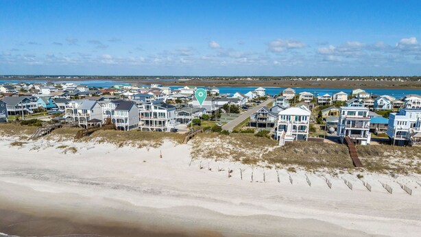 A coastal residential area with beachfront properties, a sandy beach, and a clear view of the ocean. - Steps to the beach. Canal front with new dock. Clean, Cozy Getaway.   (Surf City)