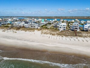 A coastal residential area with beachfront properties, a sandy beach, and a clear view of the ocean. - Steps to the beach. Canal front with new dock. Clean, Cozy Getaway. (Surf City)