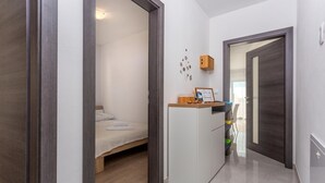 A compact hotel room with a bed, a small desk with a computer, and a wooden cabinet. - 2 bedroom amazing apartment in Mladenici (Mladenici)