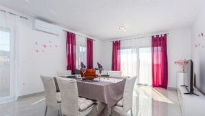 A dining area with a table set for two, white chairs, and a modern chandelier. - 2 bedroom amazing apartment in Mladenici (Mladenici)
