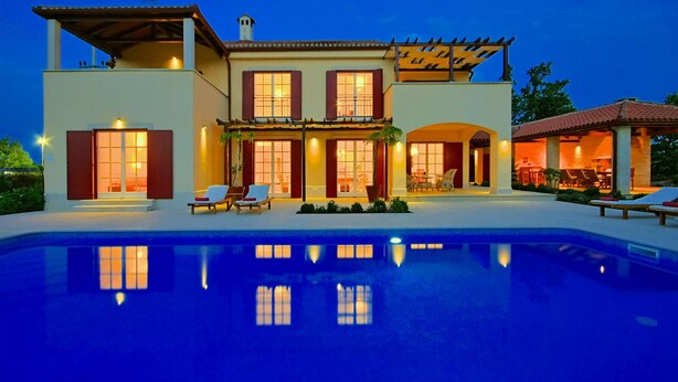 A two-story house with a swimming pool, multiple windows, and outdoor seating.