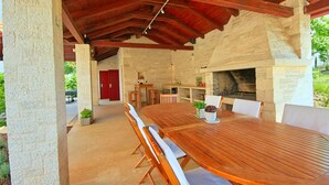 An outdoor patio with a stone wall, a wooden table, and a built-in grill.