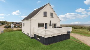 Ein zweigeschossiges Haus mit einem Balkon, einer Satellitenschüssel und Blick auf das Meer.