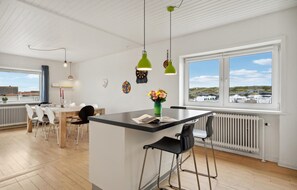 Una cocina moderna con una isla central, taburetes de bar y vistas al campo.