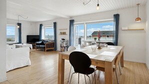 Ein modernes Wohnzimmer mit einem Holzesstisch, schwarzen Stühlen, einer Couch und einem Fernseher.