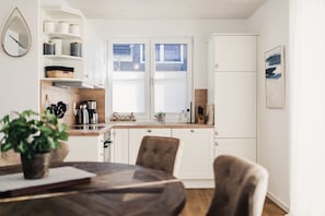 Una cocina moderna con armarios blancos, encimera de madera y una zona de comedor con una mesa redonda y sillas.