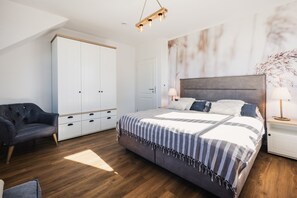 Un dormitorio con cama, armario, silla, mesita de noche y lámpara.