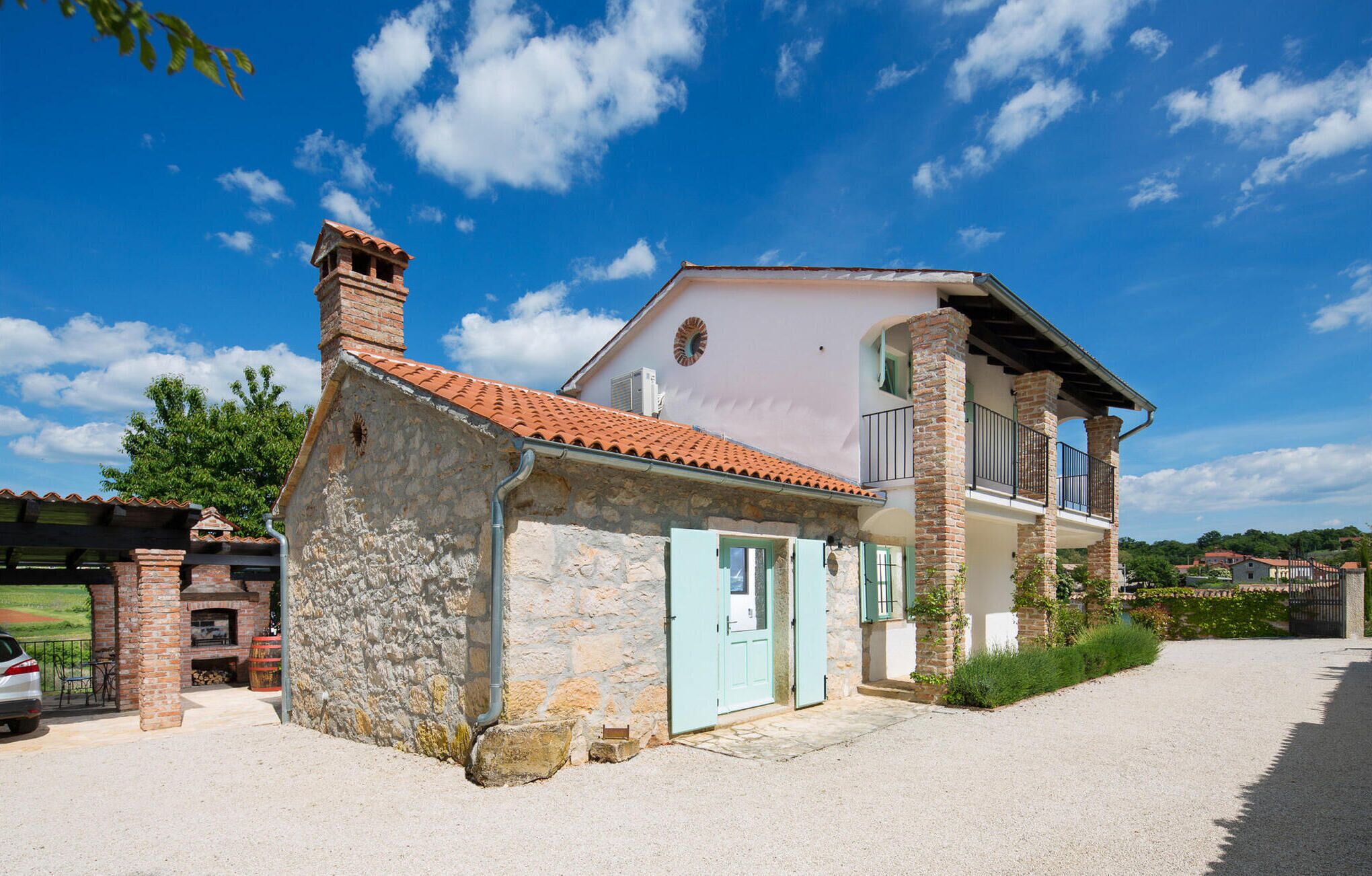 A two-story stone house with a balcony, a chimney, and a small attached structure with a brick oven.