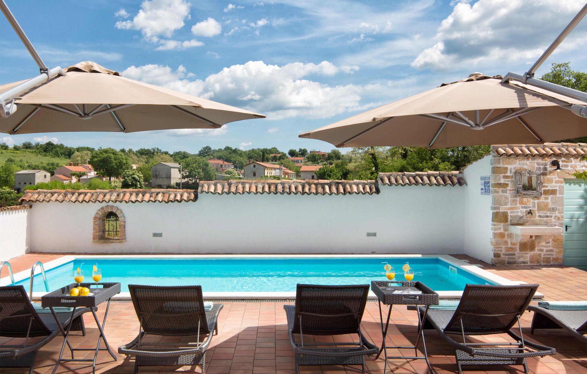 A poolside area with a clear view of the pool, lounge chairs, and umbrellas.