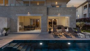 Une maison moderne à deux étages dotée d’une piscine, d’un espace salon extérieur et d’un patio.