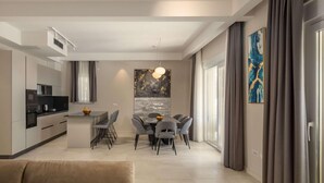 Un salon moderne comprenant un coin repas, une cuisine et une grande fenêtre avec des rideaux.