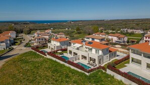 Un quartier résidentiel avec des maisons modernes, une piscine et une vue sur la mer.