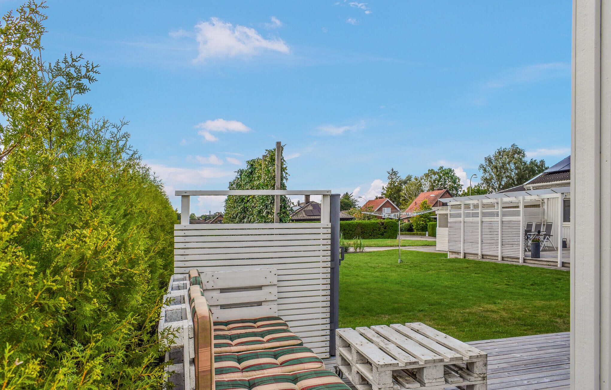 A deck with outdoor seating, a covered area, and a view of a residential neighborhood.