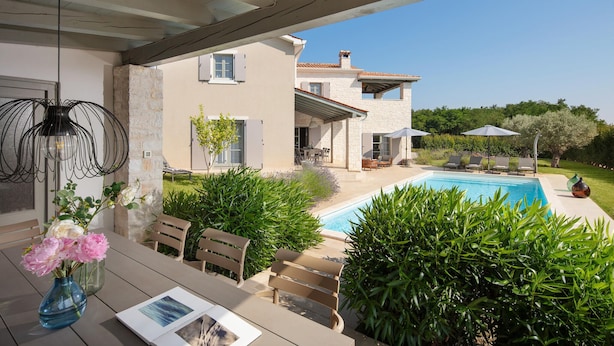 Une maison moderne dotée d’une piscine, d’un espace salon extérieur et d’un patio couvert.