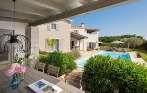 Ein modernes Haus mit Pool, Sitzgelegenheiten im Freien und einer überdachten Terrasse.