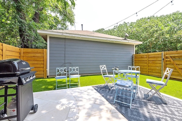 Spacious backyard with patio seating and a grill. Perfect for outdoor dining or relaxing in a private setting.
