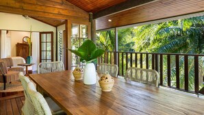 A wooden dining area with a table, chairs, and a large plant. - Papillon on Coral Sea - Have you ever imagined yourself in a treehouse? (Mossman Gorge)