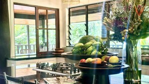 A kitchen with a central island, a stove, and a window with a view of greenery. - Papillon on Coral Sea - Have you ever imagined yourself in a treehouse? (Mossman Gorge)