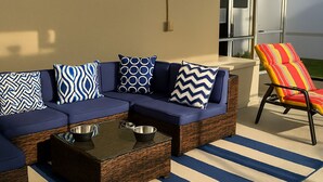 Un canapé modulable avec des coussins à motifs, une table basse en osier et un tapis rayé.