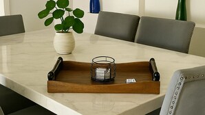 Une table à manger avec un plateau, des chaises et une plante en pot.