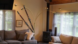Una sala de estar acogedora con techo de madera, dos sofás, una mesa de centro y una chimenea.