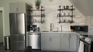 Een moderne keuken met roestvrijstalen apparatuur, grijze kastjes en een zwart aanrecht.