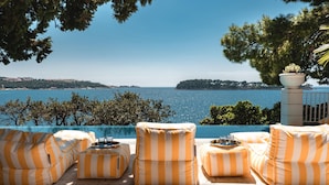 Ein Poolbereich mit gestreiften Kissen und Blick auf das Meer.