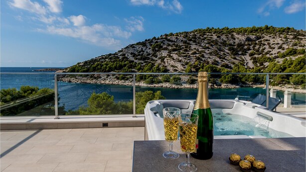 A balcony with a table set for a drink, overlooking a scenic coastal view with a mountainous backdrop. - 4 bedroom nice home in Razanj (Razanj)