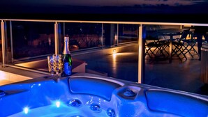 A hot tub with a bottle and glasses, a glass table, and a view of the street at night. - 4 bedroom nice home in Razanj (Razanj)