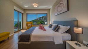 A modern bedroom with a large bed, a view of the sea, and a balcony with a chair. - 4 bedroom nice home in Razanj (Razanj)