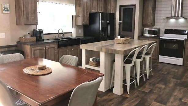 A modern kitchen with wooden cabinets, a central island with bar stools, a built-in microwave, and a stove. - "Lost Crab", beautiful 3BR, big yard, private dock (Centre)