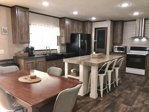 A modern kitchen with wooden cabinets, a central island with bar stools, a built-in microwave, and a stove. - "Lost Crab", beautiful 3BR, big yard, private dock (Centre)