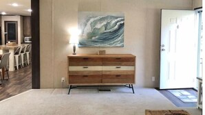A living room with a wooden dresser, a painting of a wave, and a ceiling fan. - "Lost Crab", beautiful 3BR, big yard, private dock (Centre)