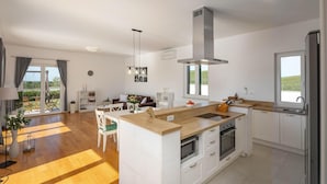 Une cuisine moderne avec des armoires blanches, un plan de travail en bois et un four encastré.