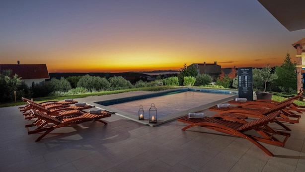 Un espace aménagé au bord de la piscine, avec des chaises longues, une petite piscine et une vue imprenable sur le coucher du soleil.