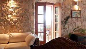A stone-walled room with a wooden door leading outside, a white sofa, and a wicker chair. - Lovely home in Orebic (Orebic)