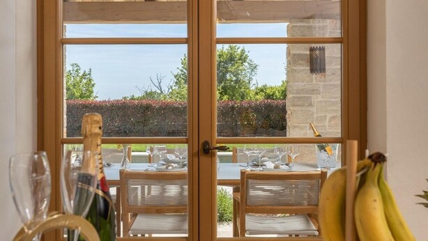 Un comedor con una mesa dispuesta para dos personas, una botella de champán y un racimo de plátanos.