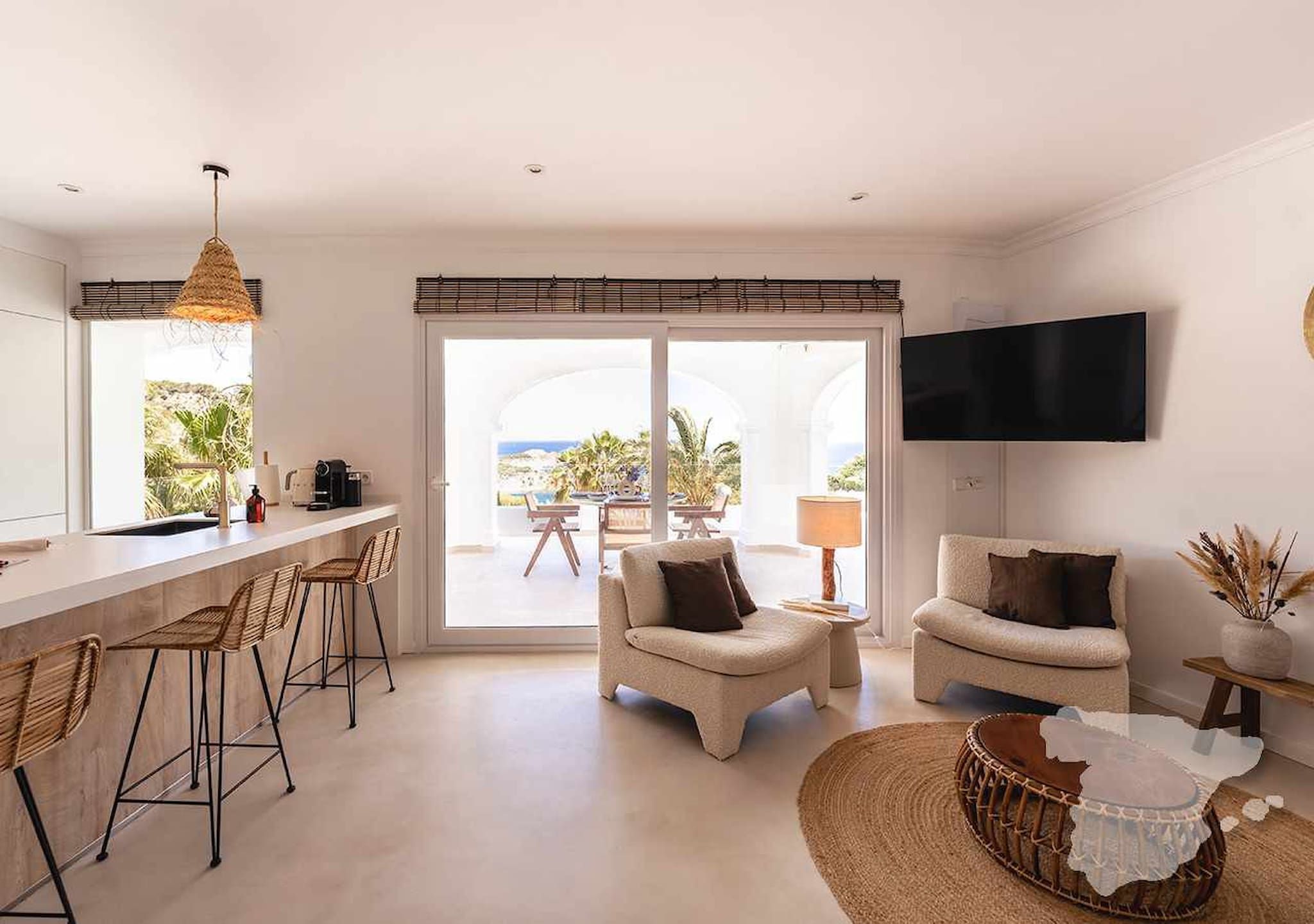 Ein modernes Wohnzimmer mit einer Couch, Sesseln und einem Essbereich mit Tisch und Stühlen.