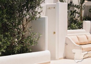 Een moderne badkamer met een witte badkuip, een douchegedeelte en een beige bank.