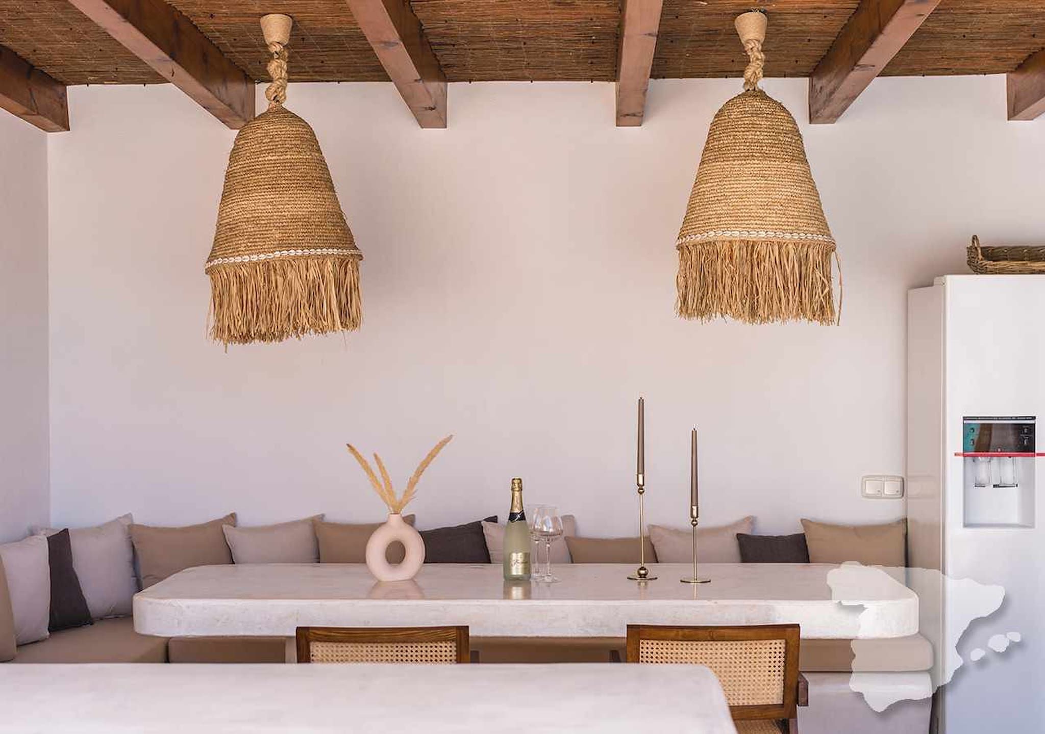 A dining area with a table, chairs, and two hanging wicker chandeliers.