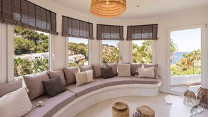 A modern living room with a curved sofa, large windows, and a view of greenery. - CostaBlancaDreams - The Jave in Javea (Javea)