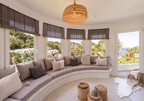 A modern living room with a curved sofa, large windows, and a hanging light fixture. - CostaBlancaDreams - The Jave in Javea (Javea)