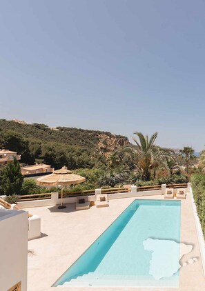 A swimming pool with lounge chairs and umbrellas, surrounded by greenery and buildings. - CostaBlancaDreams - The Jave in Javea (Javea)