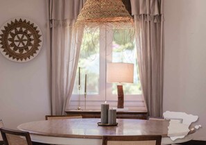 A dining area with a round table, chairs, a candle, a lamp, and a window with curtains. - CostaBlancaDreams - The Jave in Javea (Javea)