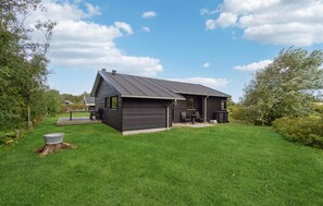 Situated in a lush setting, this cabin offers a deck with outdoor seating and a large window.