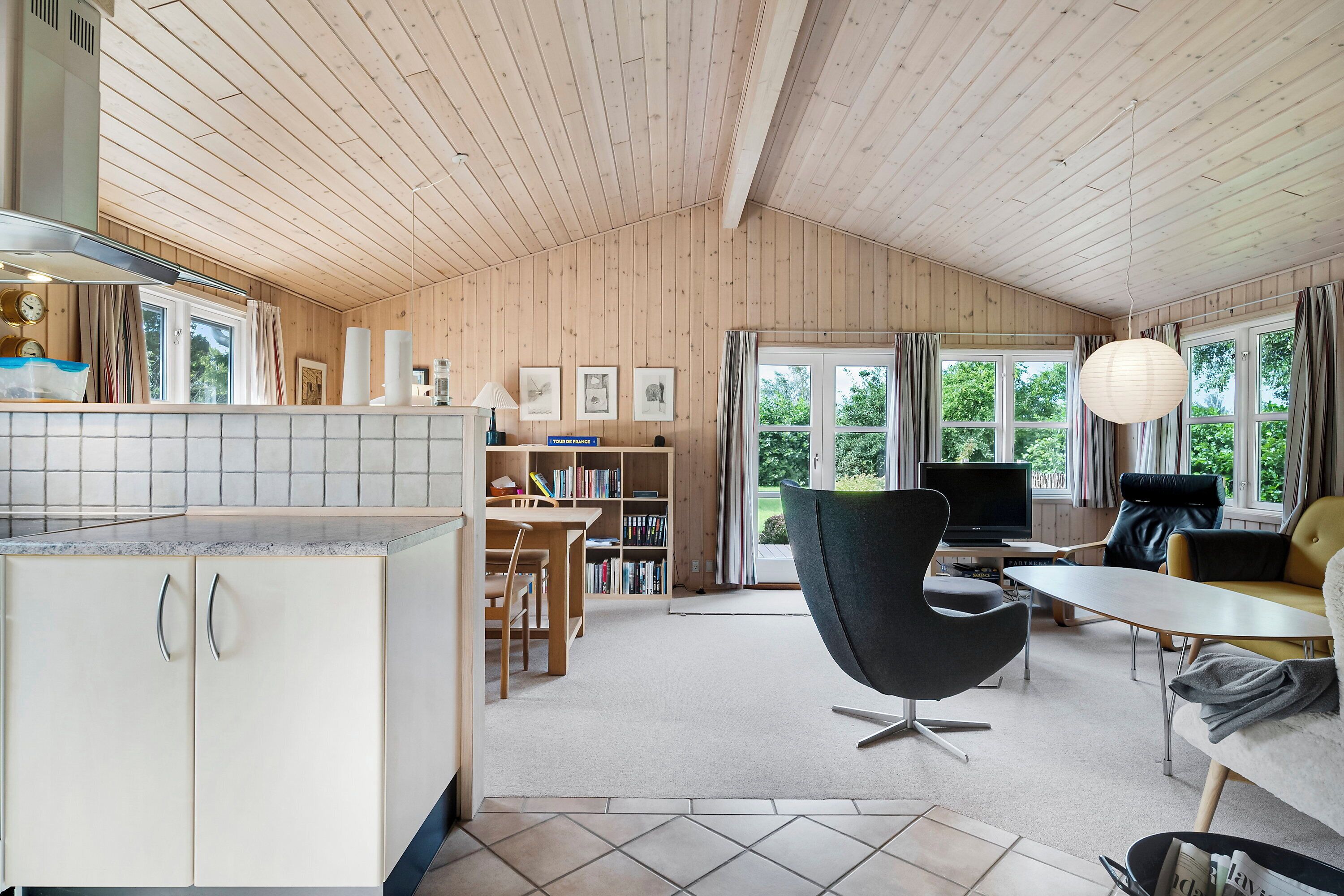 Une cuisine moderne avec des meubles en bois et un coin repas comprenant une chaise noire et un canapé.